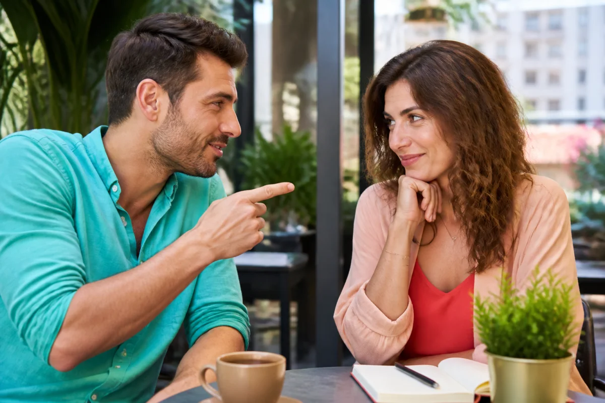 Homme taquinant une femme dans un café, échange complice illustrant pourquoi un homme provoque une femme